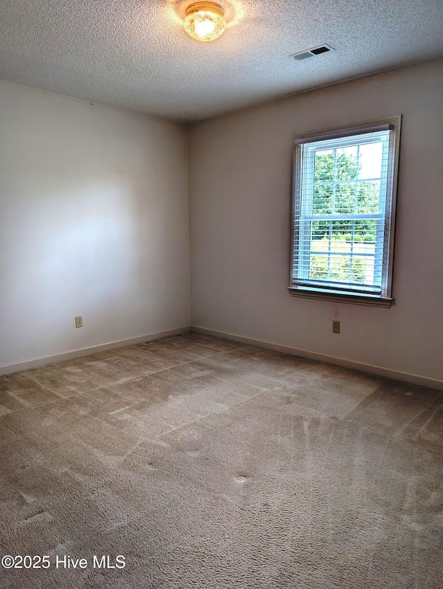 unfurnished room with a textured ceiling, carpet flooring, and baseboards