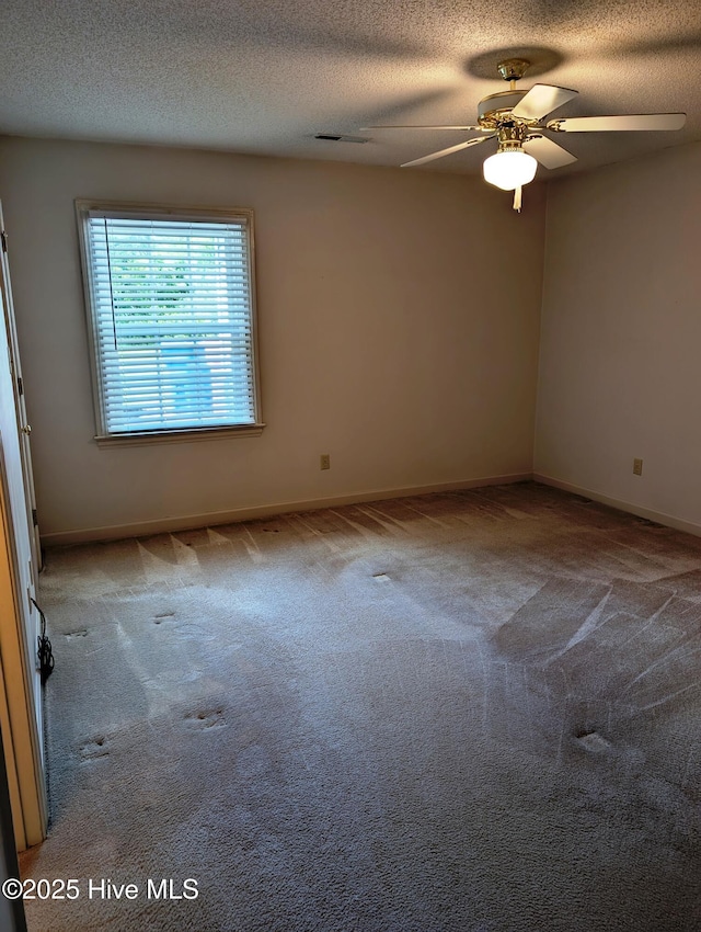 empty room featuring carpet, ceiling fan, baseboards, and a textured ceiling