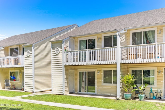 rear view of house featuring a balcony and a shingled roof