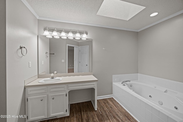 full bathroom featuring a skylight, a textured ceiling, crown molding, a tub with jets, and vanity
