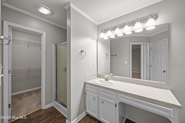 bathroom featuring a stall shower, wood finished floors, a spacious closet, vanity, and a textured ceiling