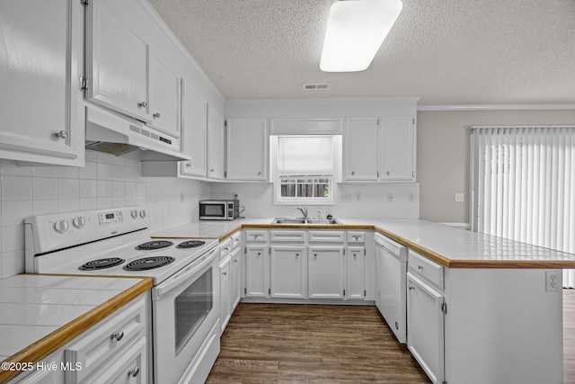 kitchen with white appliances, under cabinet range hood, a peninsula, a sink, and a textured ceiling