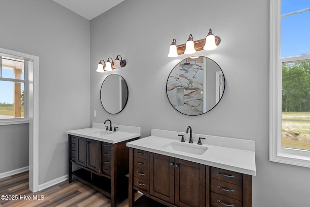 bathroom with two vanities, wood finished floors, and baseboards