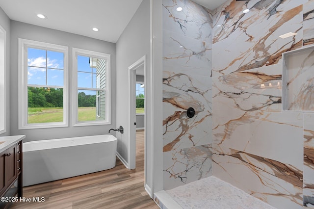 bathroom featuring vanity, a freestanding bath, recessed lighting, a marble finish shower, and wood finished floors