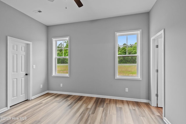 unfurnished bedroom featuring wood finished floors, multiple windows, and baseboards