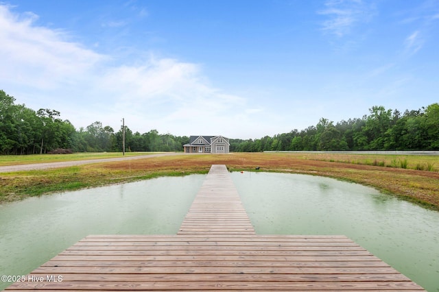 dock area featuring a water view, a lawn, and a forest view