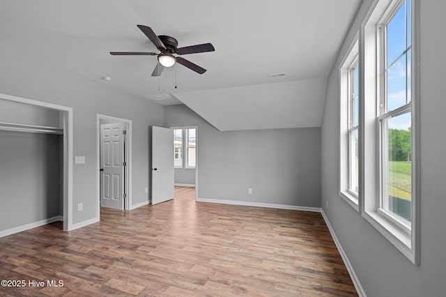 unfurnished bedroom with wood finished floors, lofted ceiling, baseboards, ceiling fan, and a closet