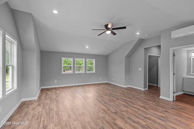 unfurnished living room featuring a wall mounted air conditioner, vaulted ceiling, ceiling fan, wood finished floors, and recessed lighting