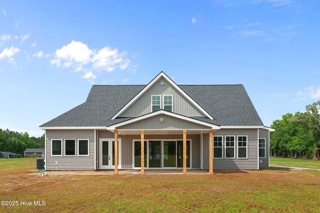 back of house featuring a yard, roof with shingles, and a patio