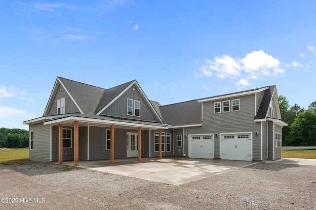view of front of home with driveway, a garage, roof with shingles, and covered porch