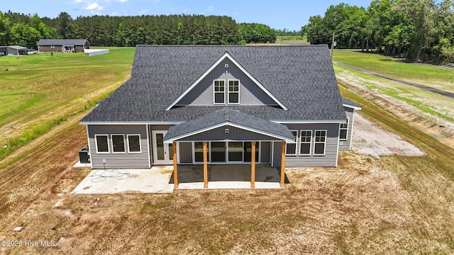 rear view of property with a patio, a shingled roof, a yard, and a forest view