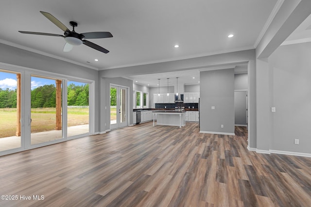 unfurnished living room with wood finished floors, recessed lighting, baseboards, crown molding, and a ceiling fan