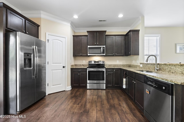202 Bungalow Rd, Holly Ridge, NC 28445 - kitchen with appliances with stainless steel finishes, a sink, light stone countertops, dark brown cabinetry, and crown molding