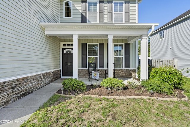 202 Bungalow Rd, Holly Ridge, NC 28445 - doorway to property with covered porch, stone siding, and fence