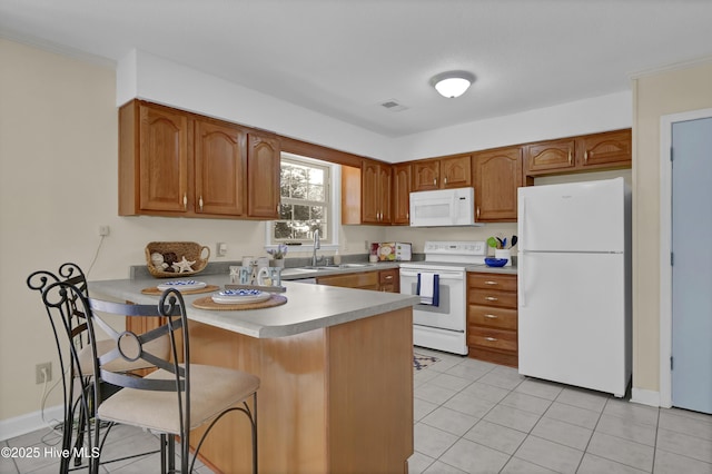 805 Hamlet Ave, Carolina Beach, NC 28428 - kitchen featuring white appliances, a peninsula, brown cabinets, a breakfast bar, and light tile patterned floors