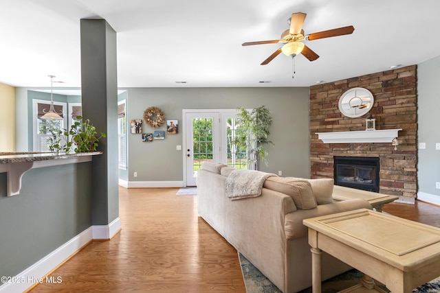 5613 Swiss Stone Ct, Wilmington, NC 28412 - living area featuring a ceiling fan, light wood finished floors, a stone fireplace, and baseboards