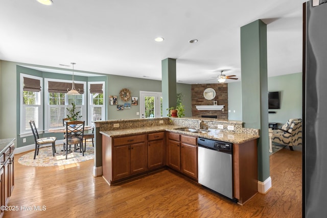 5613 Swiss Stone Ct, Wilmington, NC 28412 - kitchen featuring appliances with stainless steel finishes, a ceiling fan, brown cabinetry, light wood-type flooring, and light stone counters