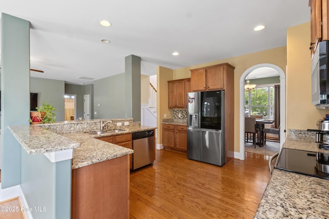 5613 Swiss Stone Ct, Wilmington, NC 28412 - kitchen with appliances with stainless steel finishes, brown cabinets, light wood-style floors, arched walkways, and recessed lighting