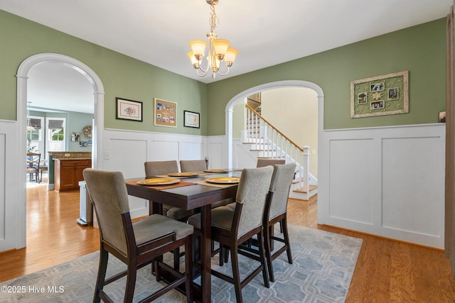 5613 Swiss Stone Ct, Wilmington, NC 28412 - dining room with arched walkways, a decorative wall, a chandelier, light wood-style floors, and stairs
