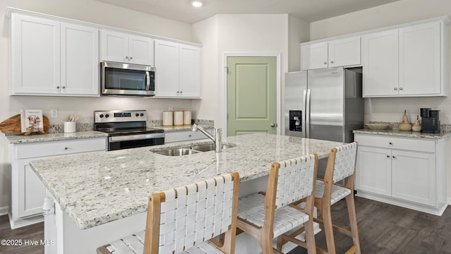 kitchen featuring stainless steel appliances, a sink, dark wood-type flooring, white cabinetry, and recessed lighting