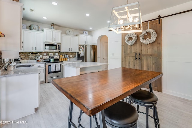 403 Stanford Ct, Maysville, NC 28555 - kitchen with stainless steel appliances, arched walkways, tasteful backsplash, white cabinets, and a kitchen island