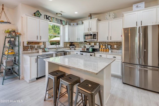 403 Stanford Ct, Maysville, NC 28555 - kitchen featuring appliances with stainless steel finishes, a sink, a breakfast bar, white cabinetry, and backsplash