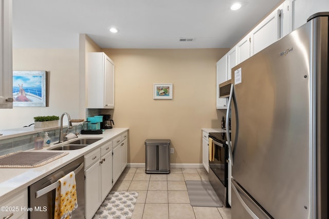 kitchen featuring stainless steel appliances, a sink, white cabinets, light countertops, and recessed lighting