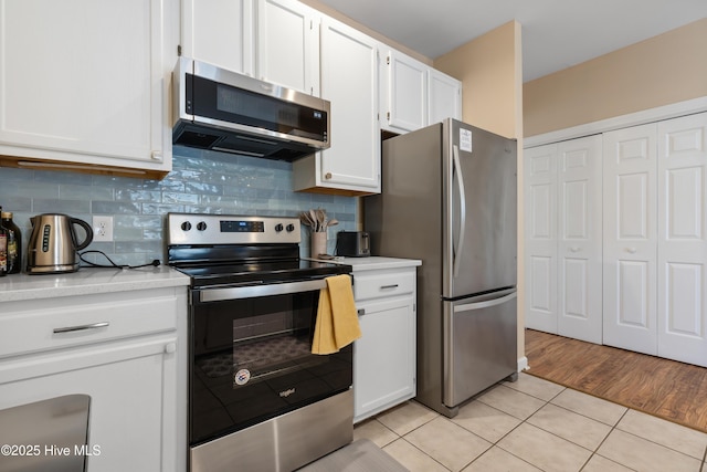 kitchen featuring appliances with stainless steel finishes, light tile patterned floors, light countertops, and white cabinets