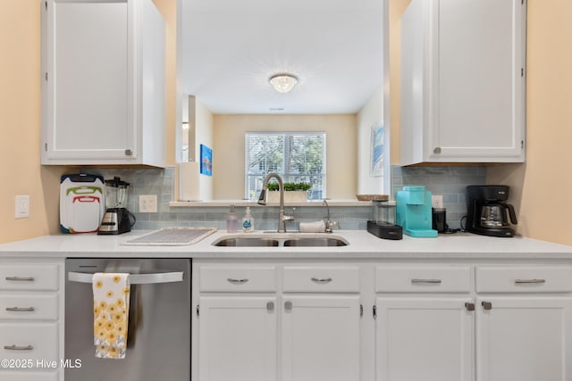 kitchen with dishwasher, a sink, backsplash, and white cabinets