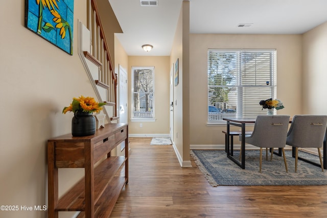 foyer with wood finished floors, healthy amount of natural light, and baseboards