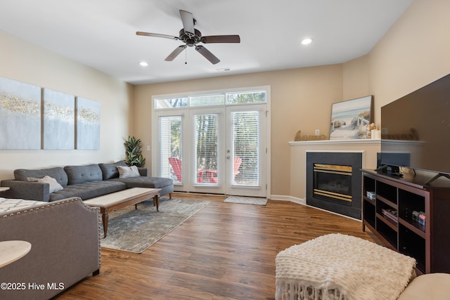 living area featuring wood finished floors, a glass covered fireplace, ceiling fan, and recessed lighting
