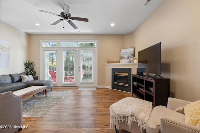 living area with recessed lighting, wood finished floors, a glass covered fireplace, a ceiling fan, and baseboards