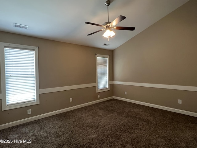 spare room with dark colored carpet, a ceiling fan, lofted ceiling, and baseboards