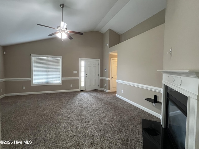 unfurnished living room with ceiling fan, vaulted ceiling, dark colored carpet, a glass covered fireplace, and baseboards