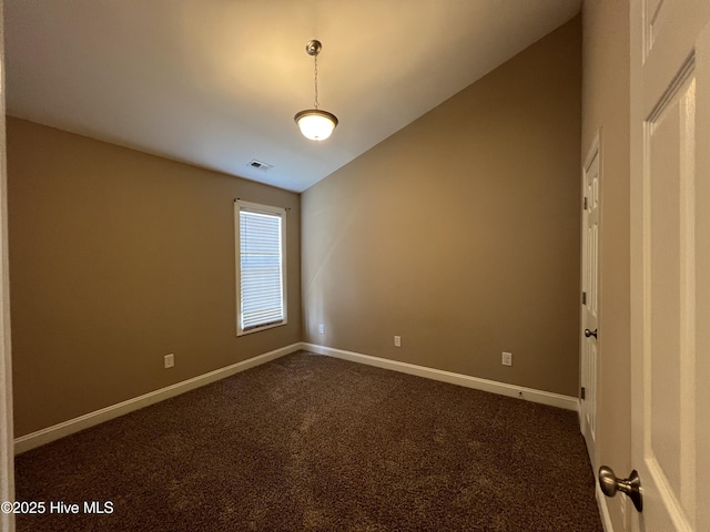 empty room featuring dark carpet, baseboards, and vaulted ceiling