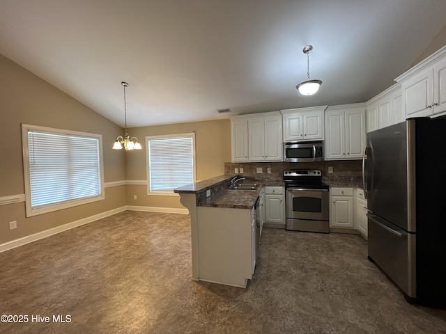 kitchen with appliances with stainless steel finishes, a peninsula, a sink, white cabinetry, and vaulted ceiling