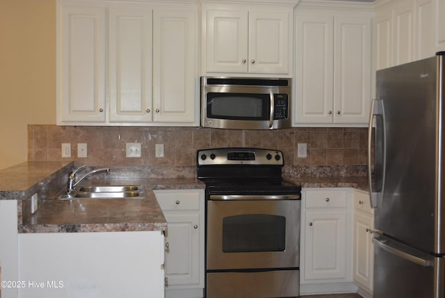 kitchen featuring stainless steel appliances, a sink, white cabinetry, decorative backsplash, and dark countertops
