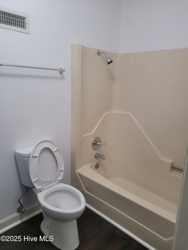 bathroom featuring toilet, shower / washtub combination, and wood finished floors