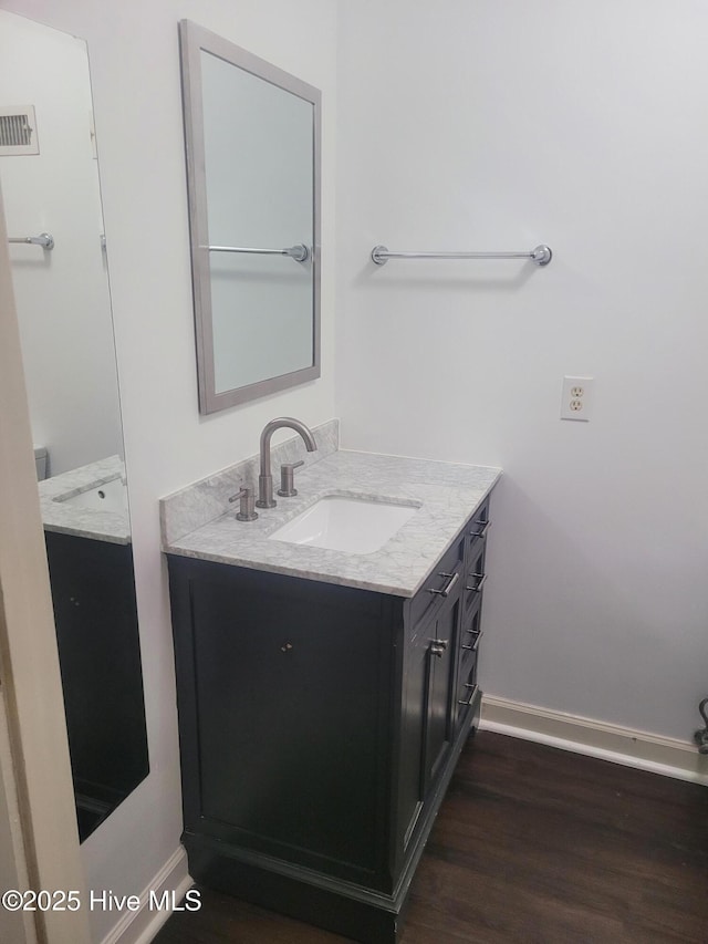 bathroom with vanity, wood finished floors, and baseboards