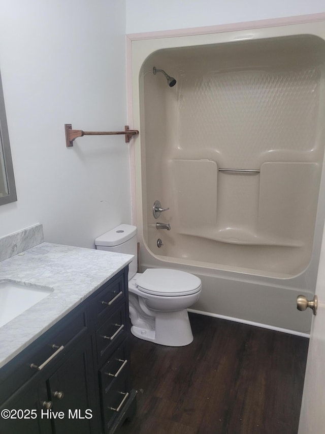 bathroom featuring wood finished floors, vanity, toilet, and tub / shower combination