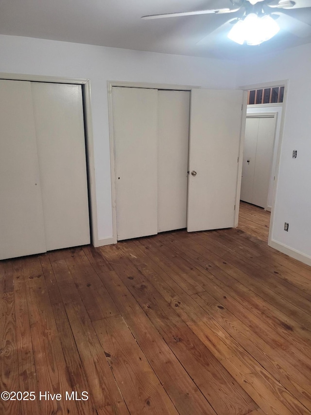 unfurnished bedroom with multiple closets and hardwood / wood-style floors