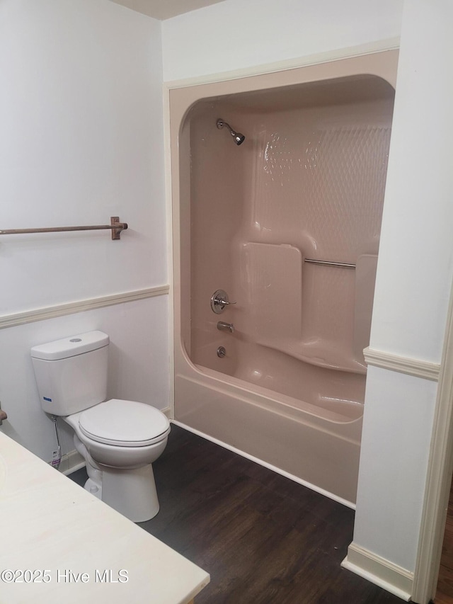 full bath featuring toilet, wood finished floors, and shower / bath combination