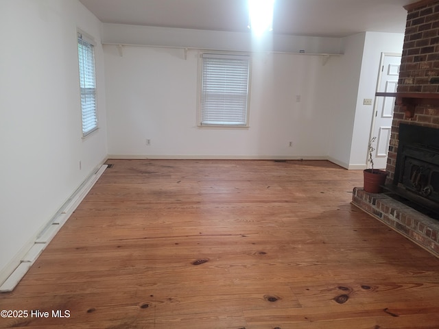 unfurnished living room featuring wood finished floors, baseboards, and a fireplace