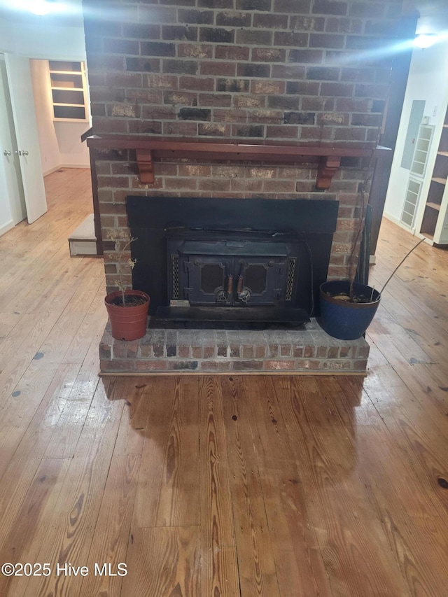 detailed view of a fireplace, wood finished floors, and baseboards