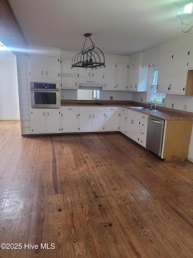 kitchen featuring appliances with stainless steel finishes, under cabinet range hood, a sink, dark wood-type flooring, and white cabinets
