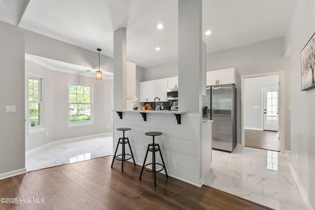 kitchen with stainless steel appliances, light marble finish floors, a breakfast bar area, baseboards, and recessed lighting