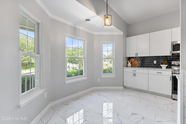 kitchen with stainless steel appliances, baseboards, light countertops, light marble finish flooring, and crown molding