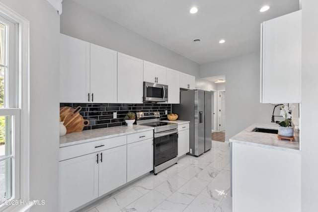 kitchen featuring appliances with stainless steel finishes, light marble finish floors, tasteful backsplash, recessed lighting, and white cabinetry