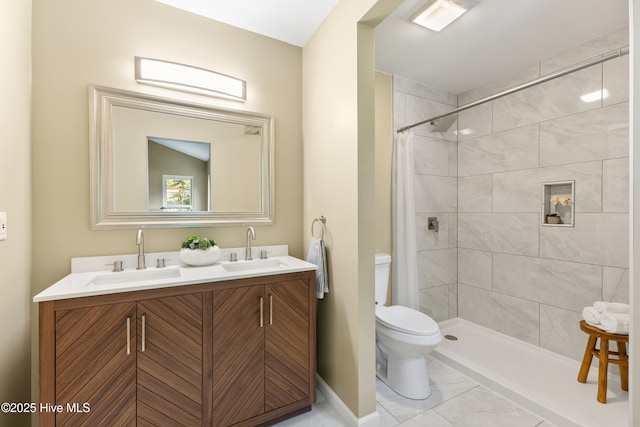 bathroom with toilet, tiled shower, baseboards, marble look tile flooring, and double vanity