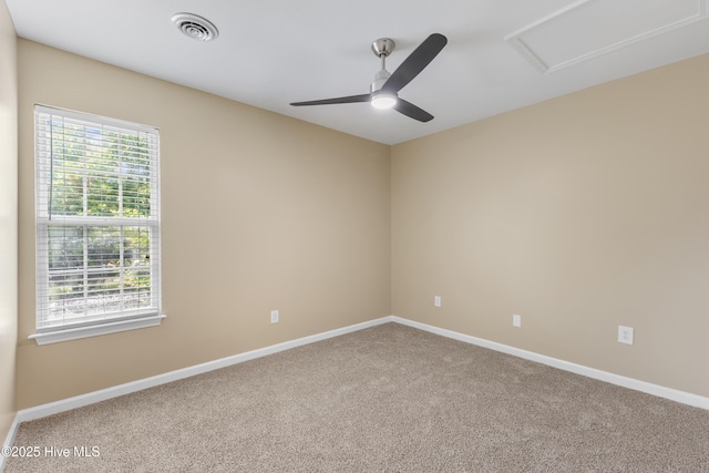 carpeted spare room with attic access, a ceiling fan, and baseboards